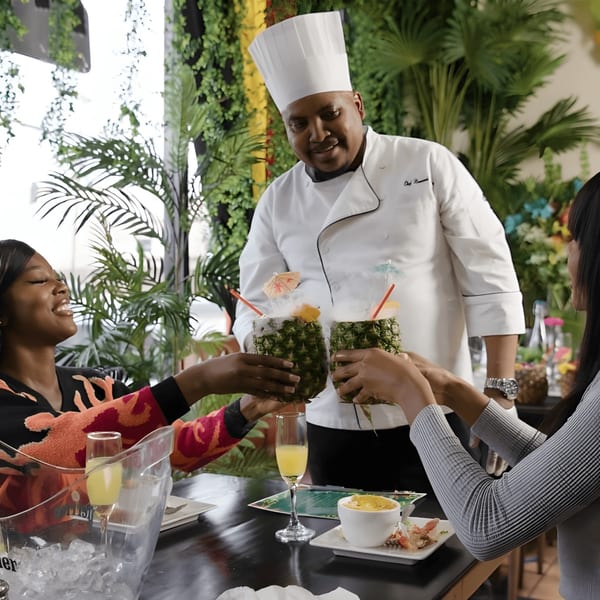 Chef serving two women smoking pineapple drinks at Taste of the Caribbean restaurant.