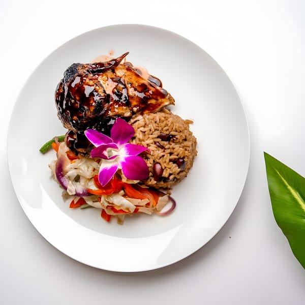 Caribbean jerk chicken with rice and peas, vegetables, and an orchid garnish on a white plate.