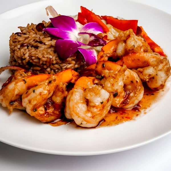 Caribbean jerk shrimp with rice and peas, garnished with a purple orchid and red bell peppers.