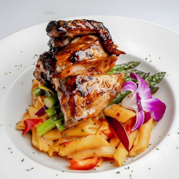Caribbean jerk chicken with penne pasta, asparagus, bell peppers, and a purple orchid garnish.